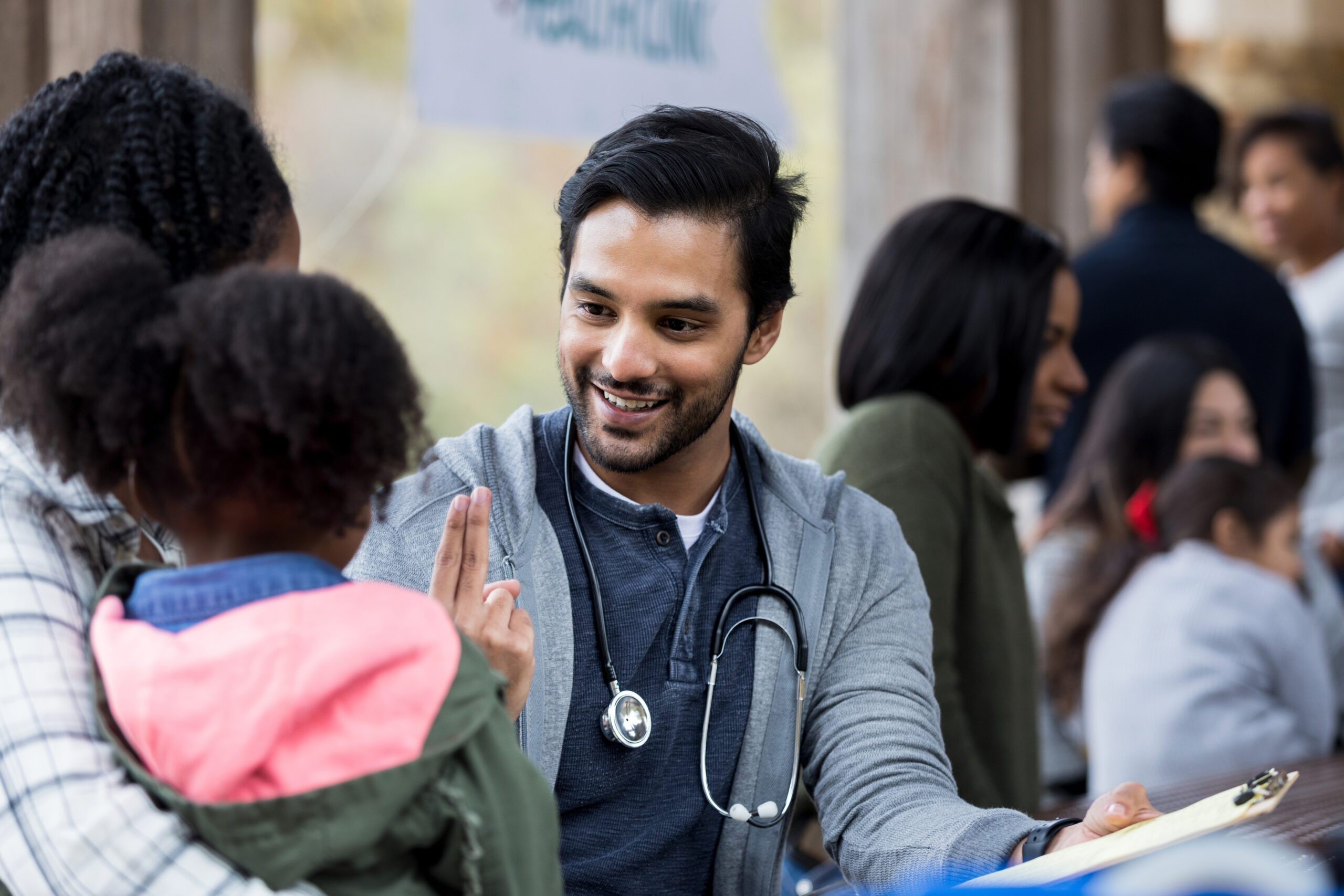 Smiling medical student volunteers assisting elderly woman in wheelchair, showcasing compassion and community engagement.