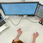 Female programmer coding at her desk using two desktops and a laptop.