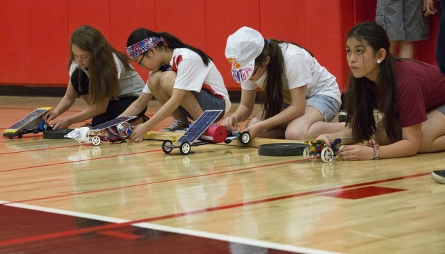 Students participating in the Junior Solar Sprint race, showcasing their designed solar cars.